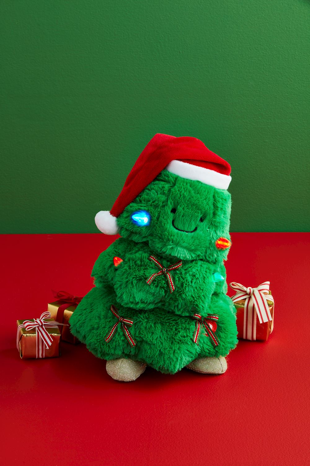 Light-Up Singing Tree toy with polyester leaves, plastic trunk, green silhouette, and battery compartment.