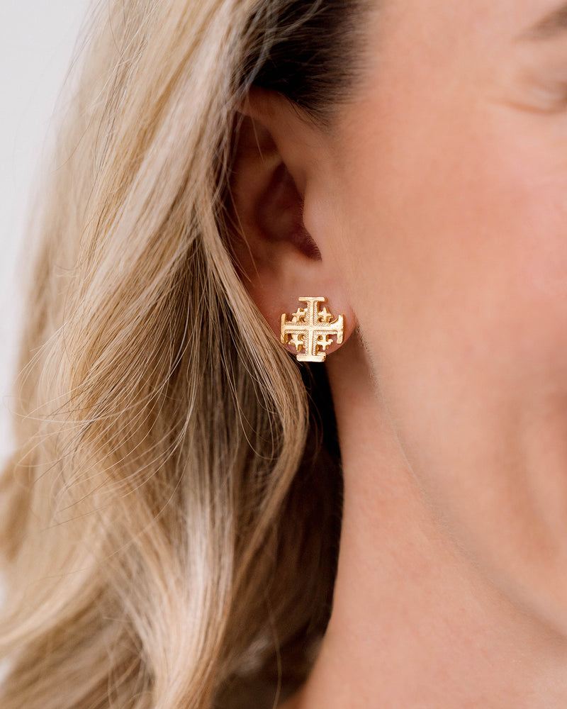 Close-up of a person wearing a gold multi cross stud earring with a post back.
