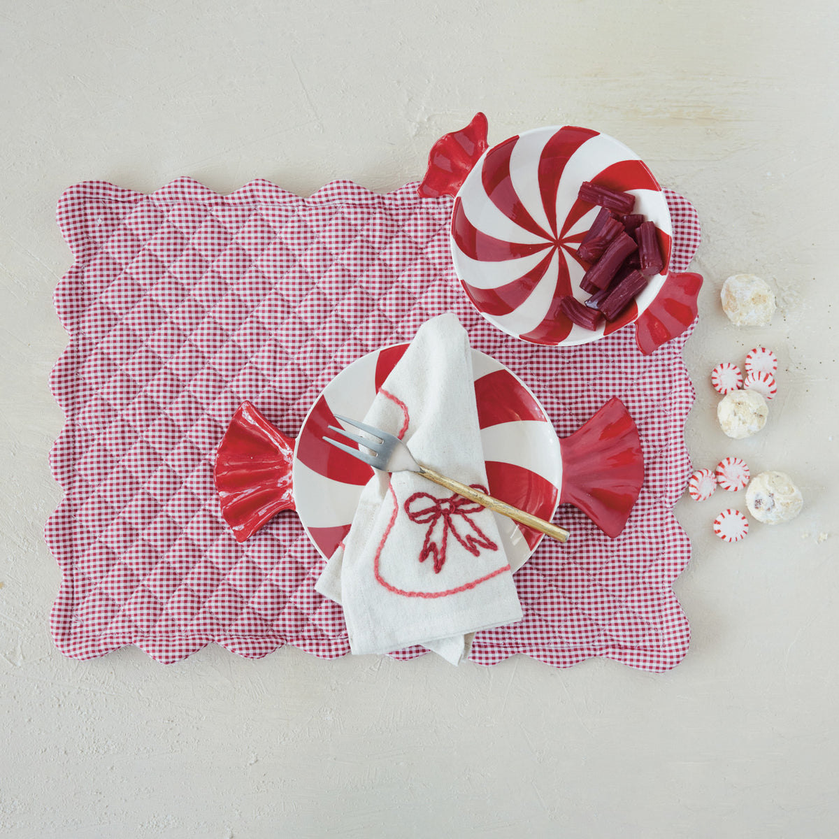 Hand-painted red and white candy-shaped ceramic plate on a red gingham placemat.