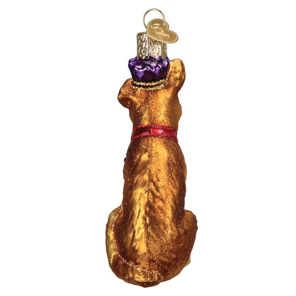 Red ceramic dog ornament with gold accents hanging on a Christmas tree branch.