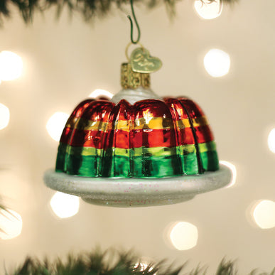 Festive gelatin mold glass ornament with red, yellow, and green layers on a white plate.