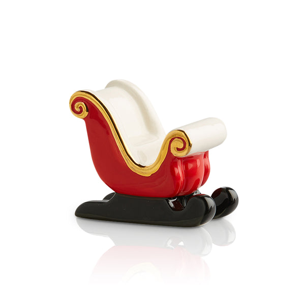 Red and white ceramic sleigh with gold trim and black runners, a festive holiday decor.
