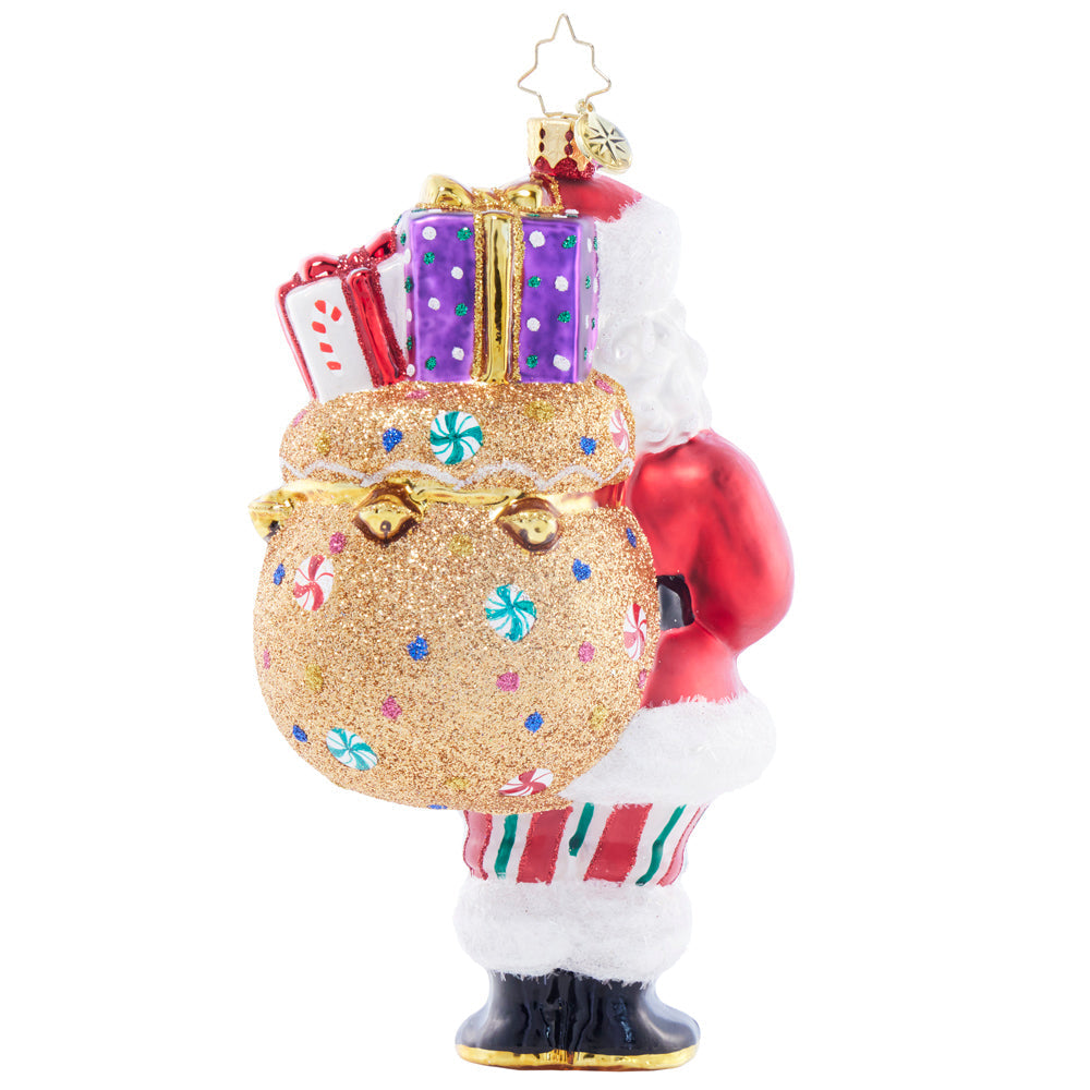 Santa glass ornament carrying a glittery gold gift bag with presents and candy details.