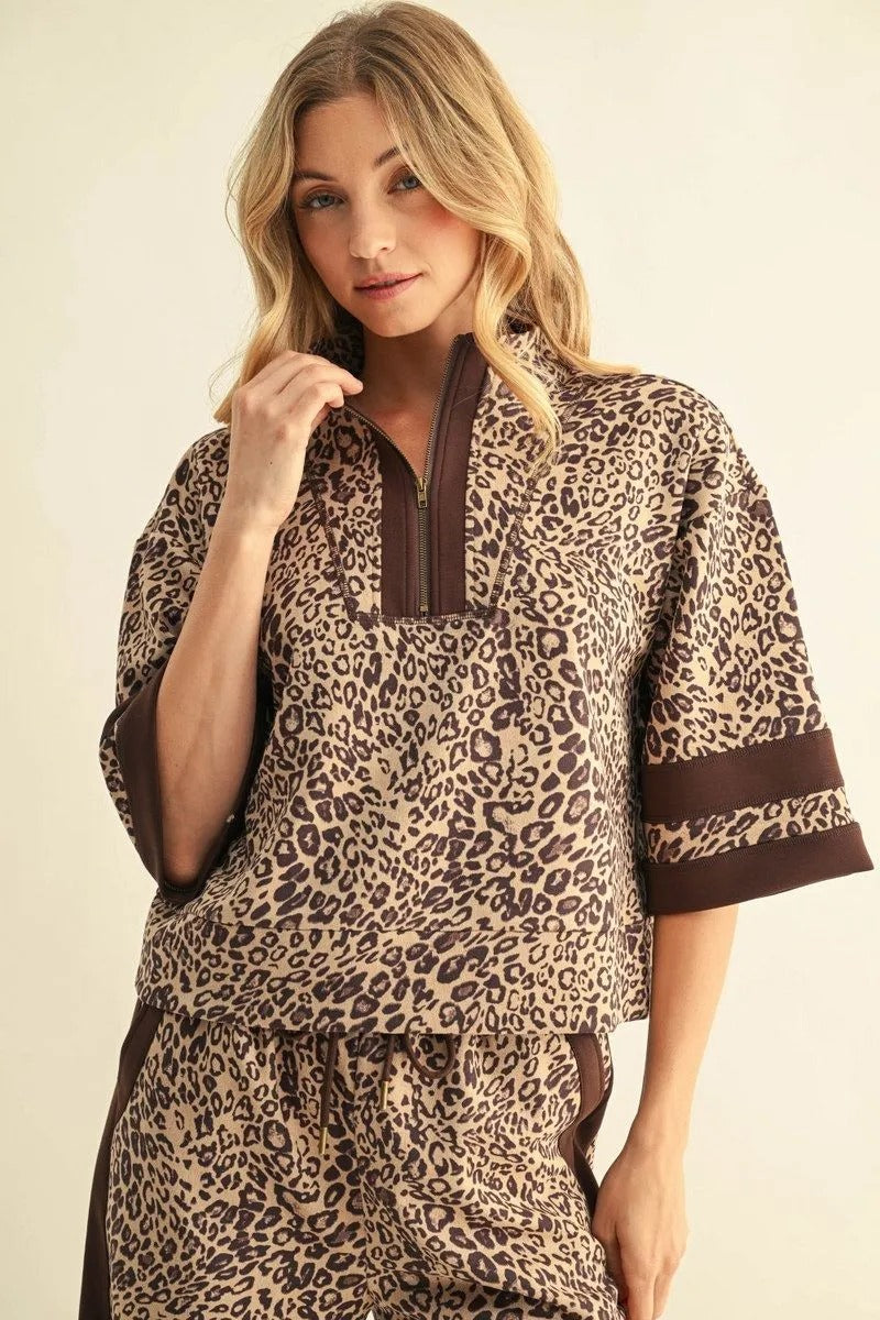 Woman wearing a leopard print faux suede top with a half-zip neckline and brown contrast trim.