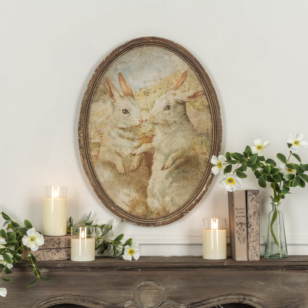 Oval framed duo print featuring two bunny silhouettes on paper with a wood frame.