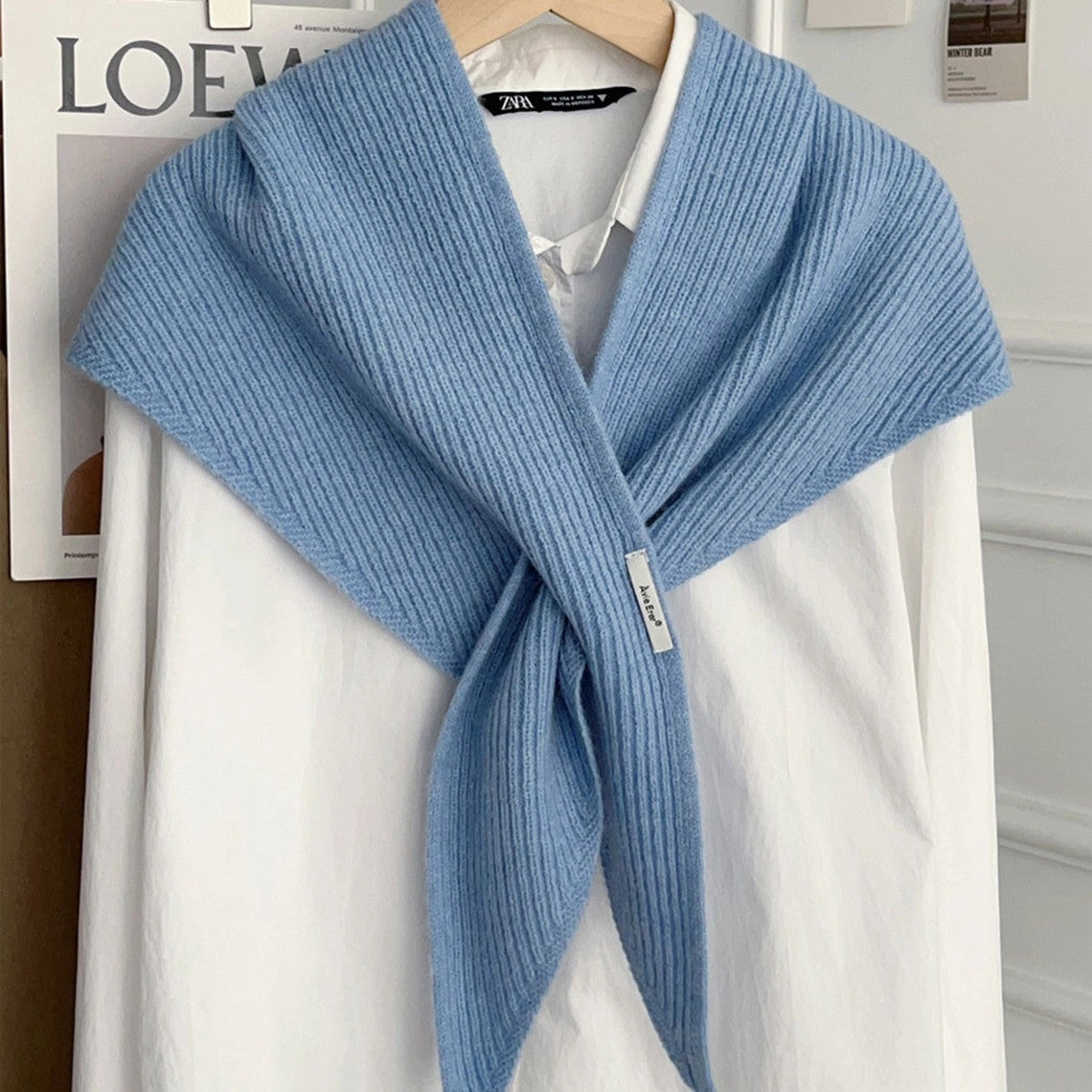 Light blue knitted solid cross triangle shawl draped over a white button-down shirt.