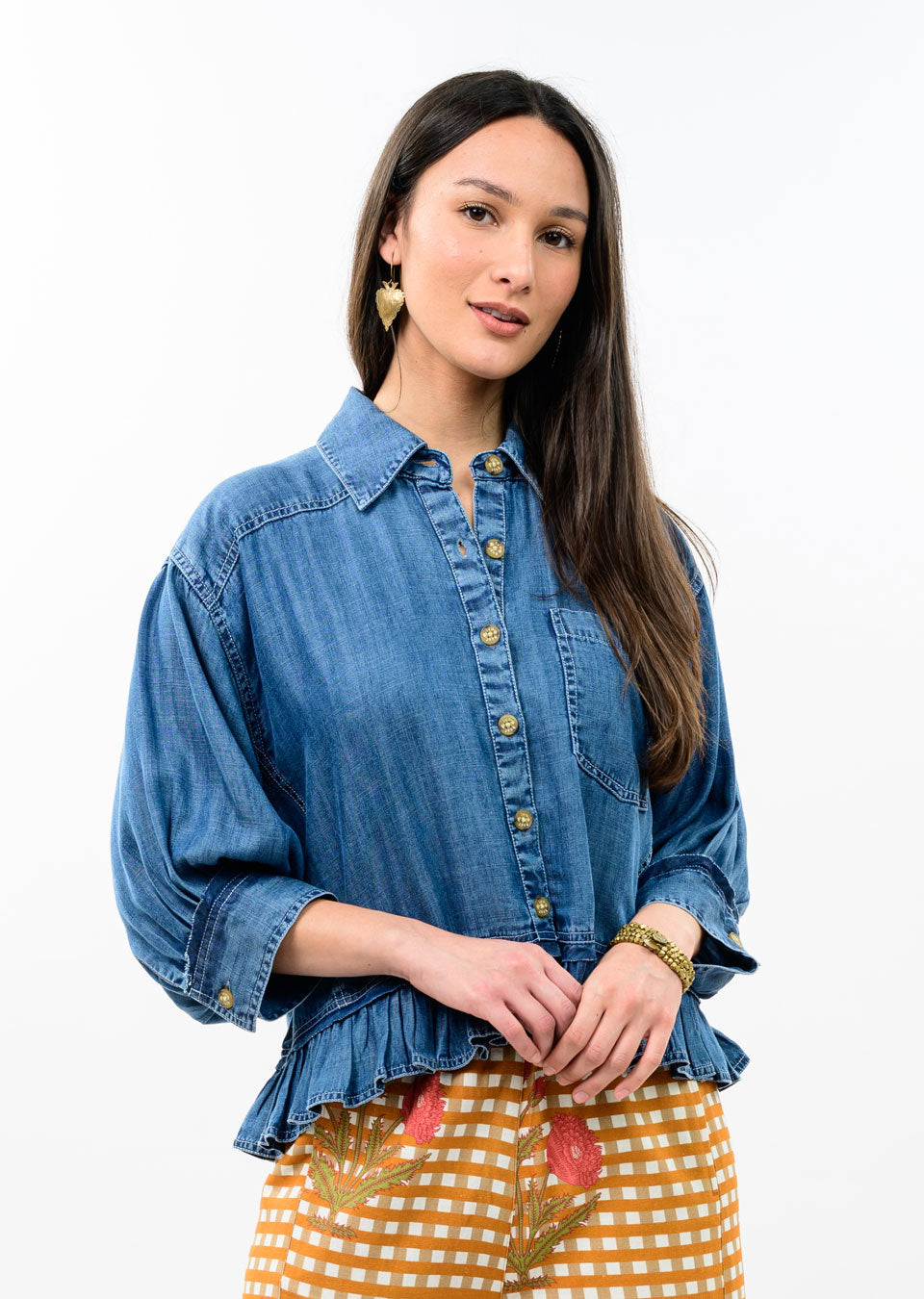 Woman wearing a blue denim jacket with a button-down front and a ruffled peplum hem.