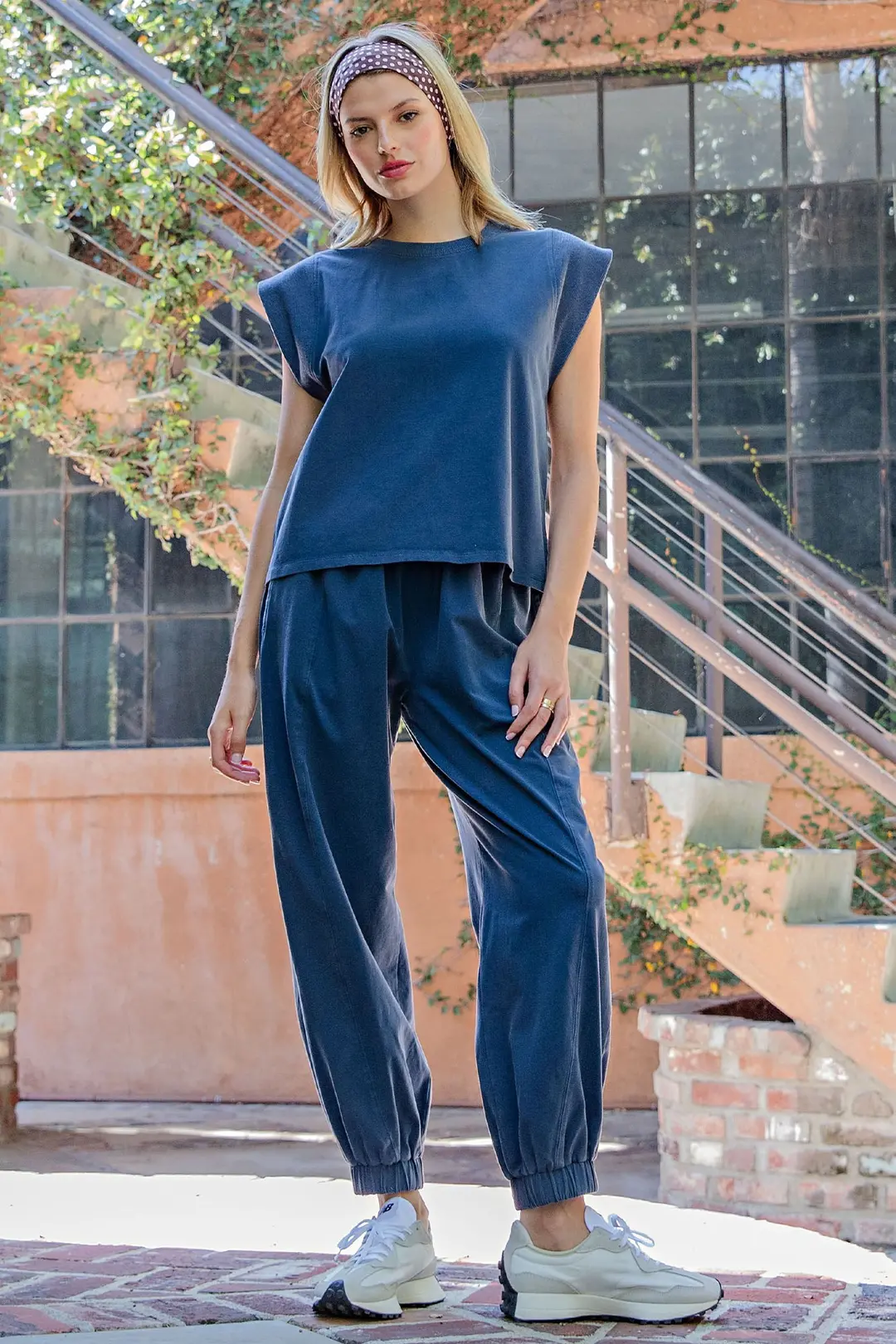 Woman wearing a navy blue Briella Ribbed Trim Cap Sleeve Top with matching joggers and sneakers.