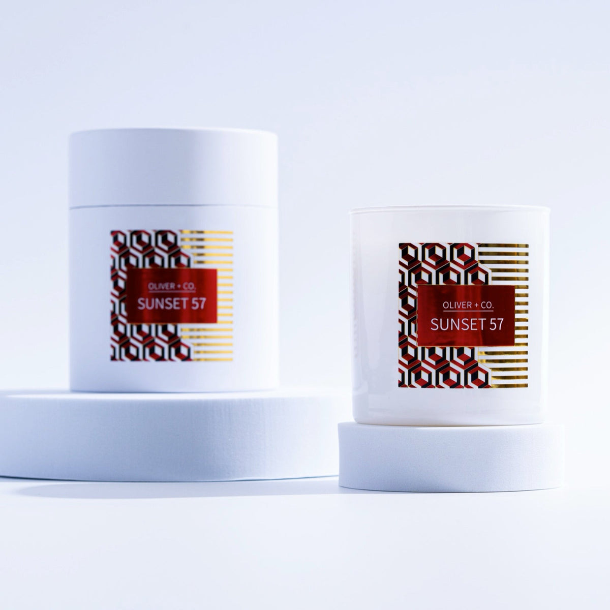 12 oz Signature Candle in white glass and matching cylindrical box with red Sunset 57 label.