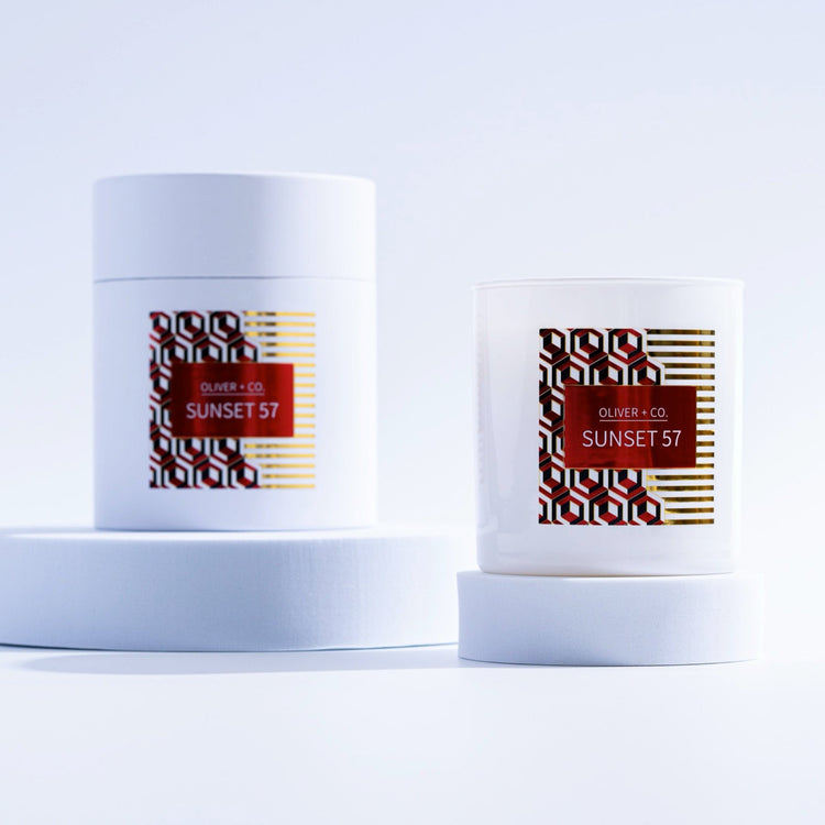 12 oz Signature Candle in white glass and matching cylindrical box with red Sunset 57 label.