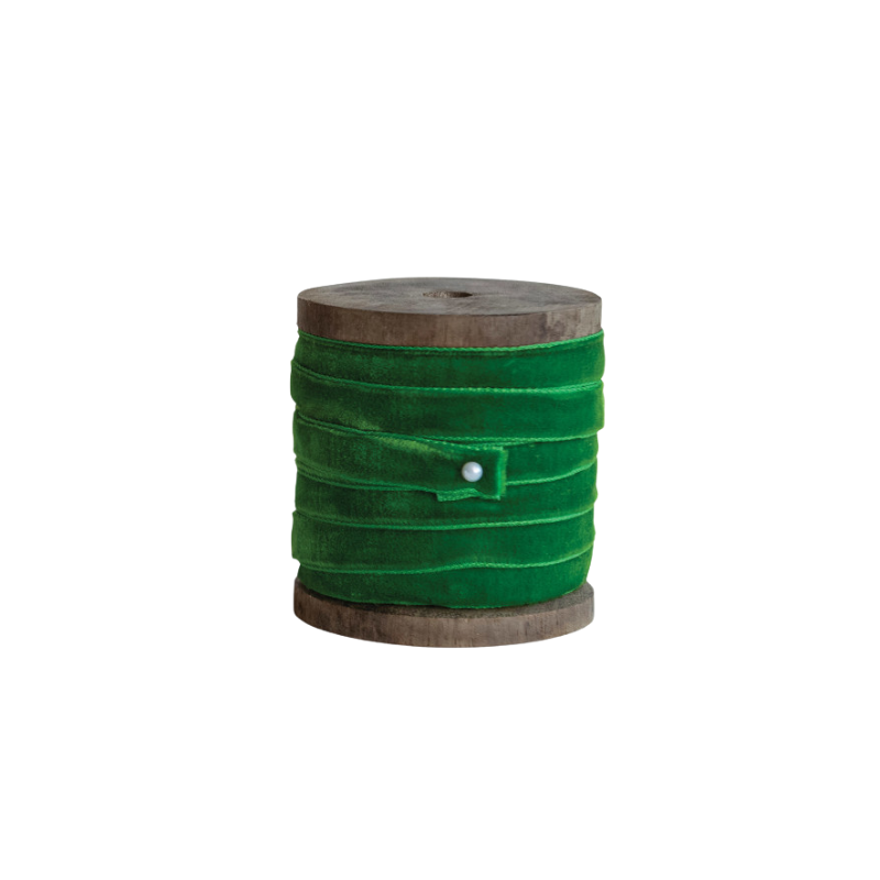 Green velvet ribbon wrapped around a rustic wooden spool with a white pin fastener.