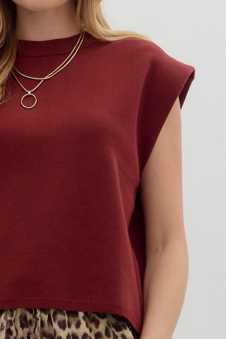 Close-up of a burgundy crewneck knit muscle tee top with a gold necklace and leopard print pants.