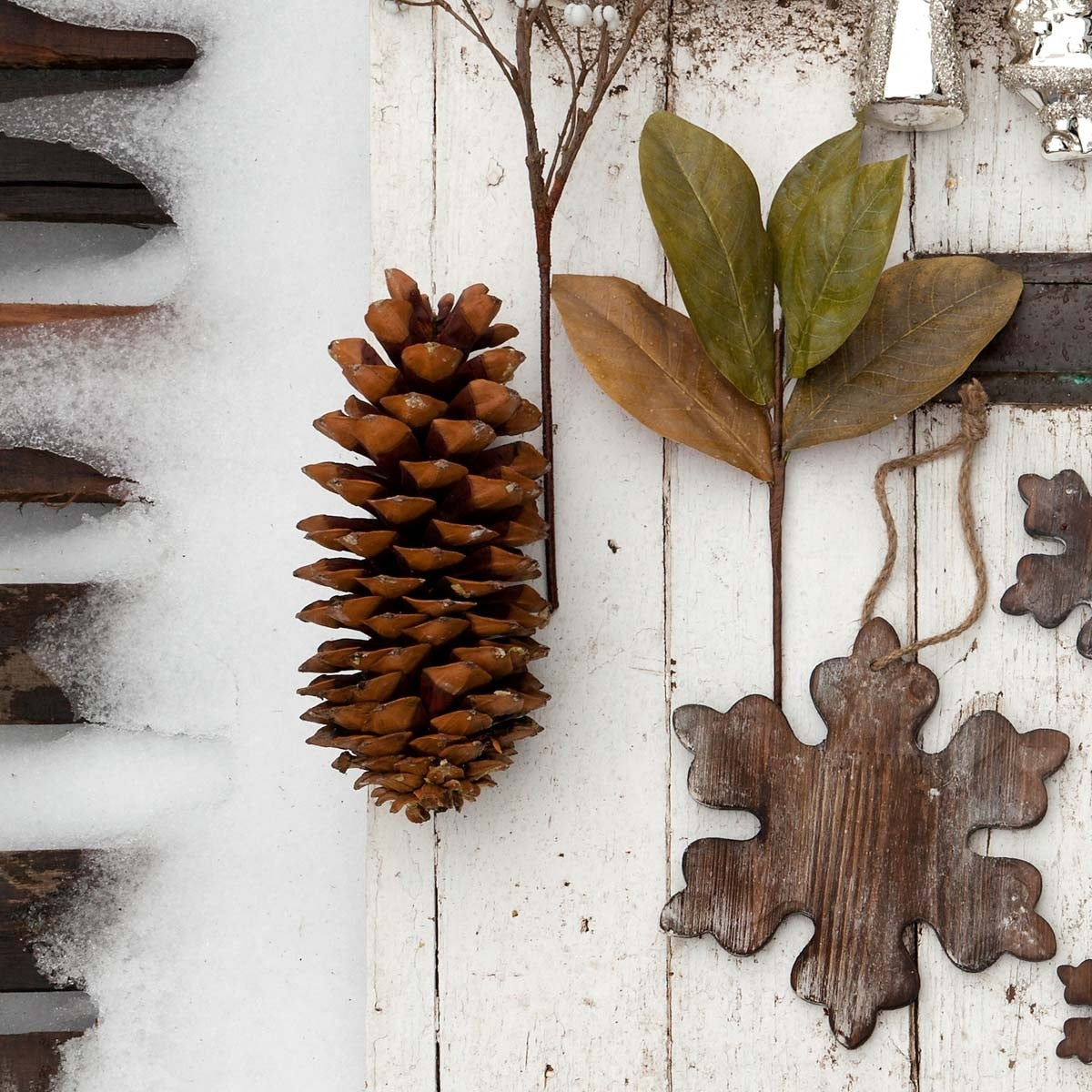 Large brown Sugar Pine Cone displayed on a white wooden surface with winter decor and snow.