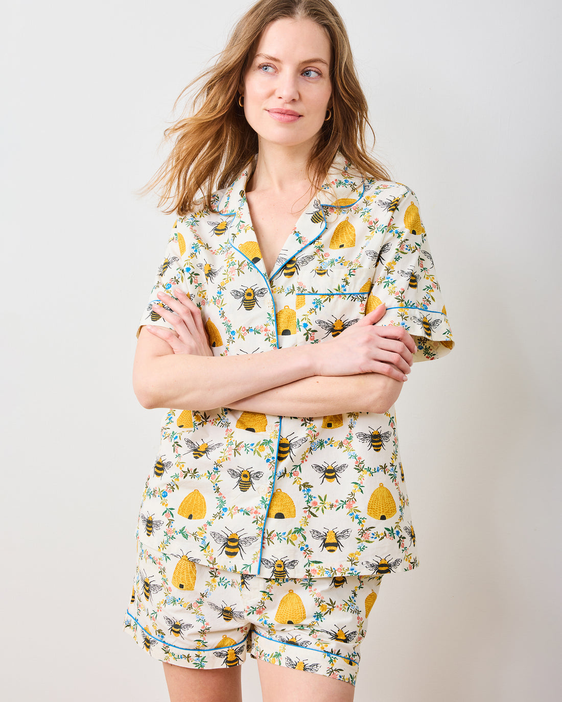 Woman wearing a white organic cotton short pajama set with a yellow bee and beehive print.