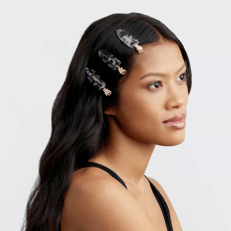 A woman wearing three black and white marbled creaseless hair clips in her long dark hair.
