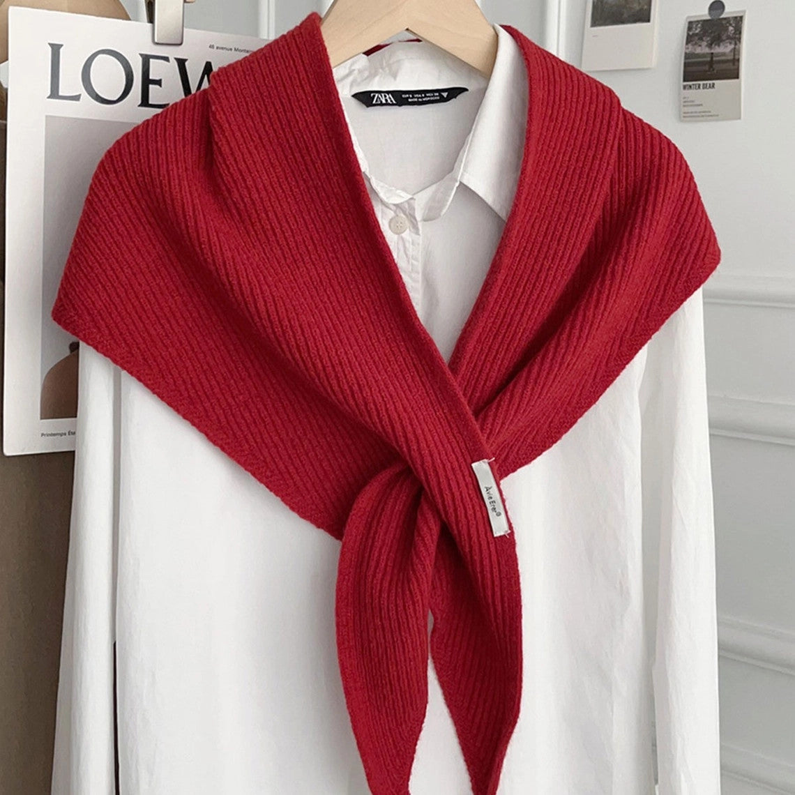 Red knitted solid cross triangle shawl draped over a white button-down shirt on a hanger.
