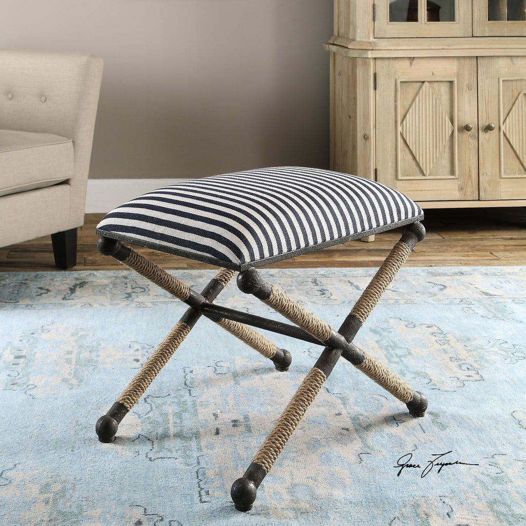 X-frame bench with navy and white striped cushion and rope-wrapped legs.