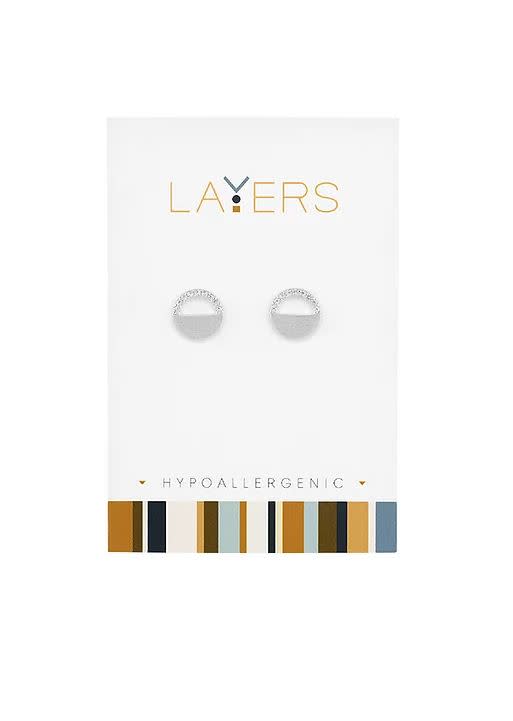 Silver CZ half circle stud earrings on a white Layers brand display card.