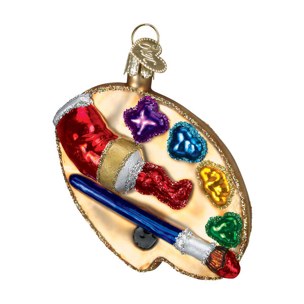 Glass artist's palette ornament with colorful paint dollops, a paintbrush, and a red paint tube.