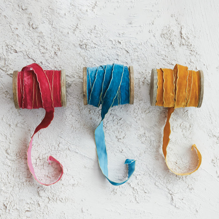 Three spools of 3/4 inch velvet ribbon in red, blue, and gold with metallic edges on wood spools.