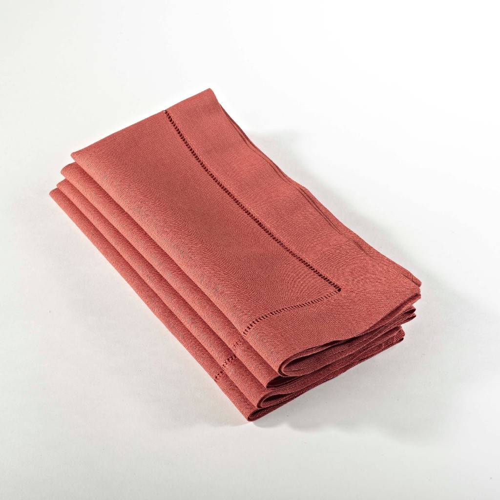 Stack of four rust-colored hemstitched linen dinner napkins.