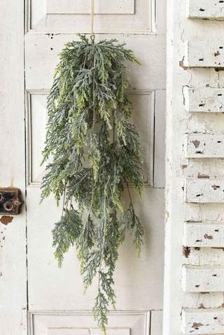 A 27-inch bent bough cedar hanging decoration with frosted green foliage on a white paneled door.