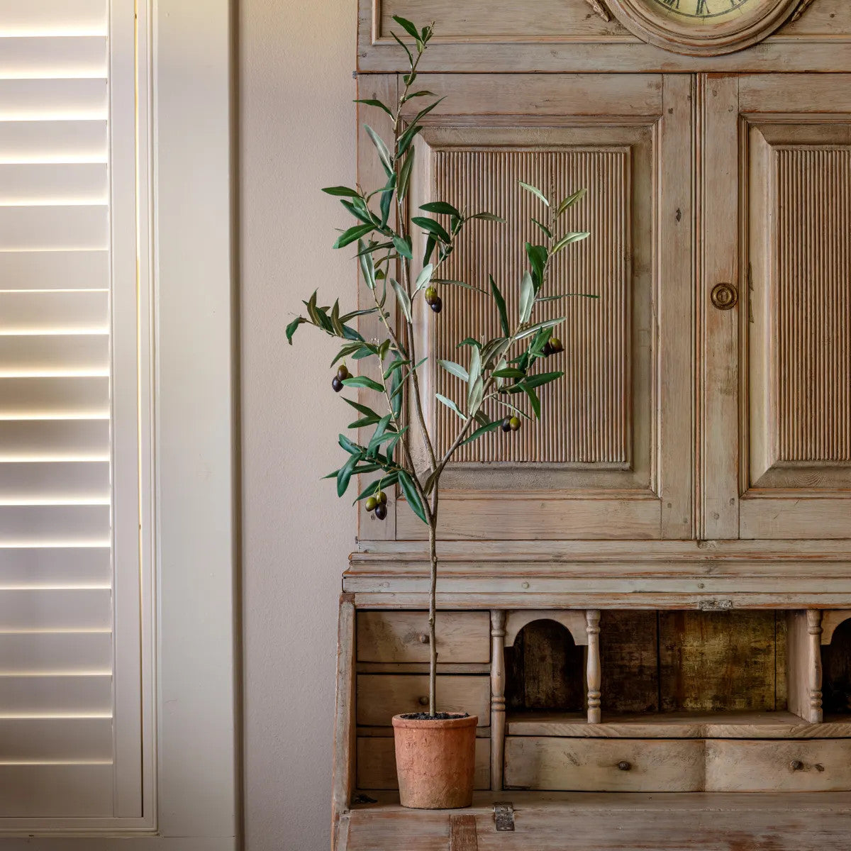 Potted olive tree in a plastic pot with polyester foliage.