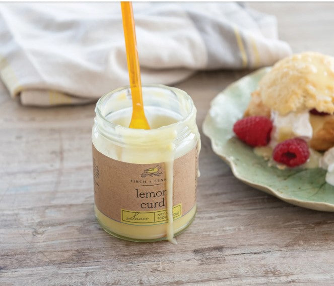 A jar of bright yellow lemon curd sauce with a white lid.