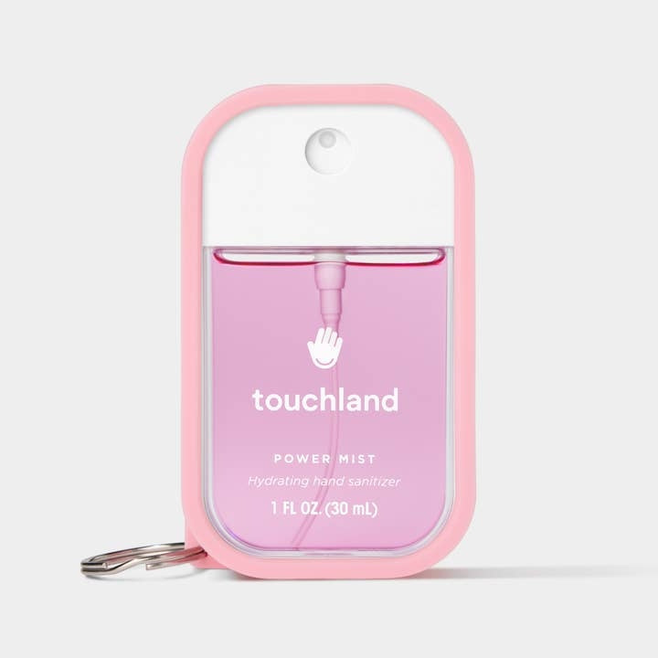 Bubblegum pink rubber-silicone case with a metal keyring holding a Touchland hand sanitizer mist.
