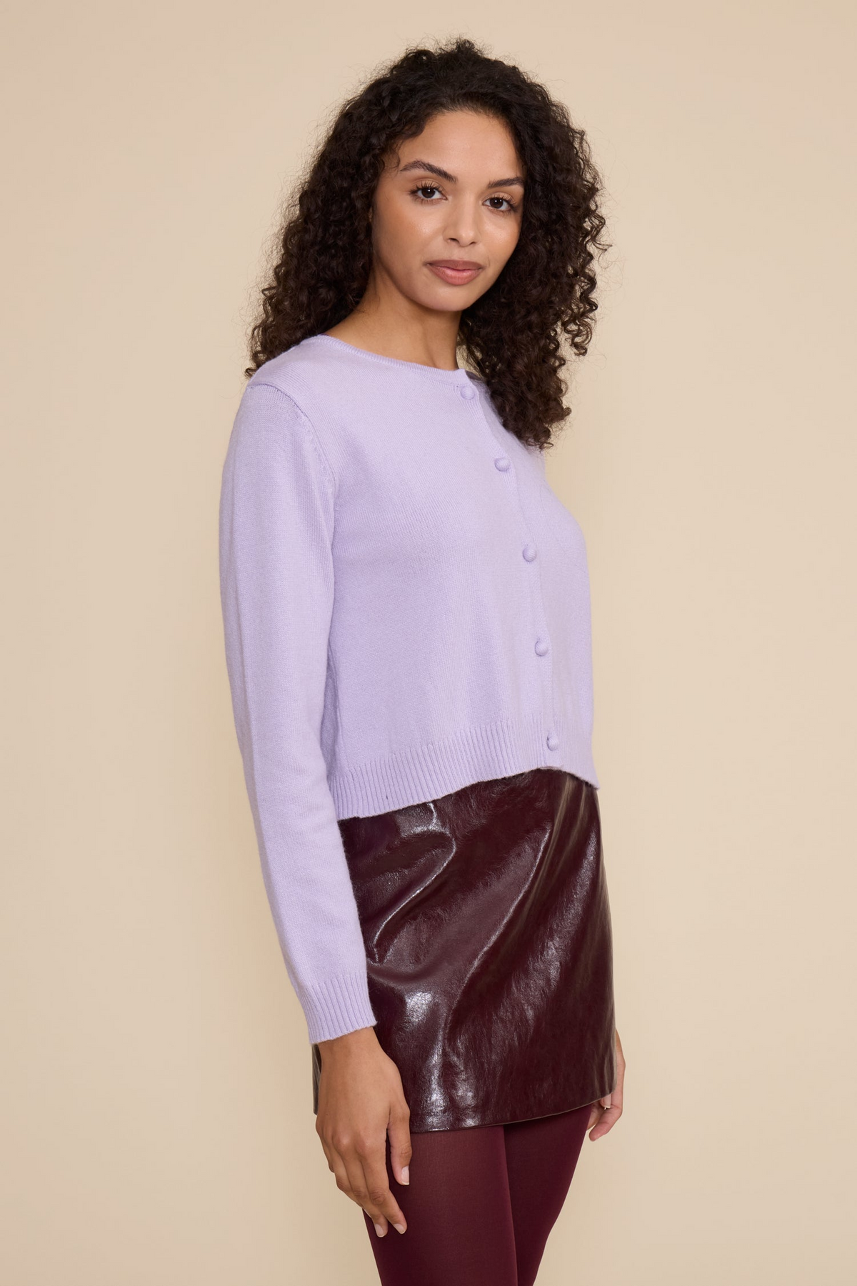 A woman wearing the light purple Lucy Judd Cardigan with a dark burgundy leather skirt.
