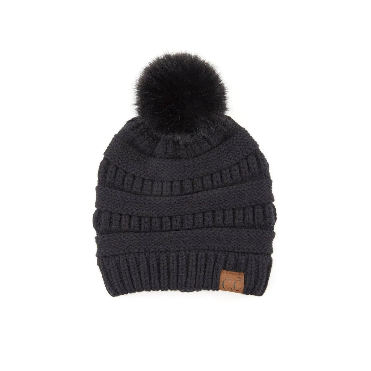Black cable knit beanie with faux fur pom on a minimalist background
