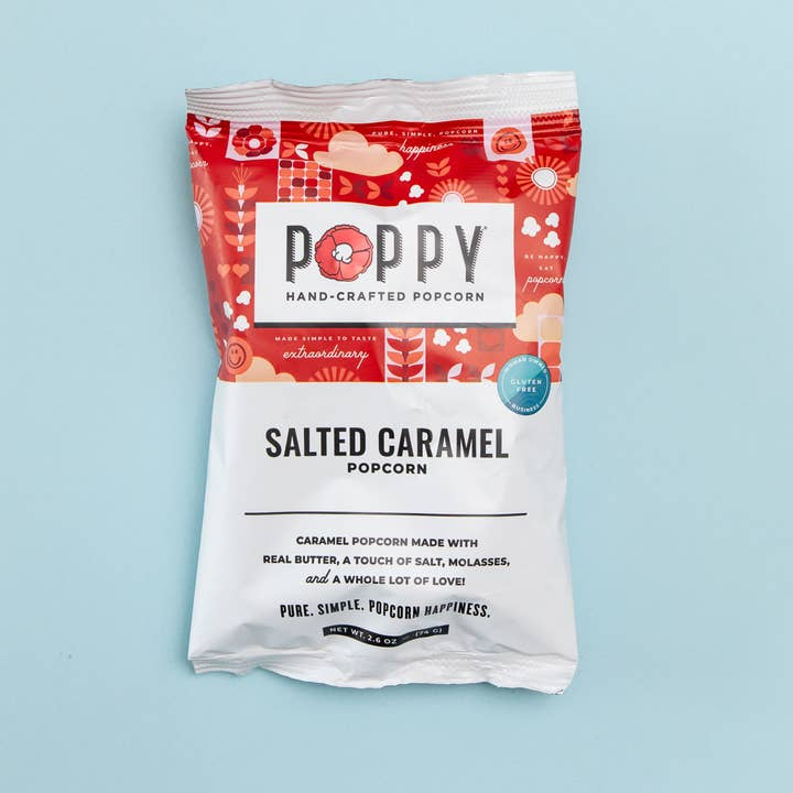 A 2.6 oz bag of Poppy Hand-Crafted Salted Caramel Popcorn against a light blue background.