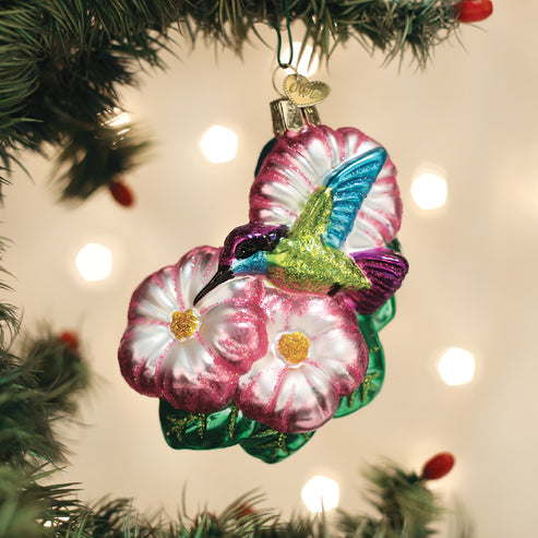 Magnificent Hummingbird glass ornament with pink flowers hanging on a Christmas tree.