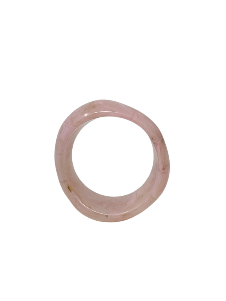 A thick, light pink marbled acrylic bangle bracelet shown from a top-down perspective.