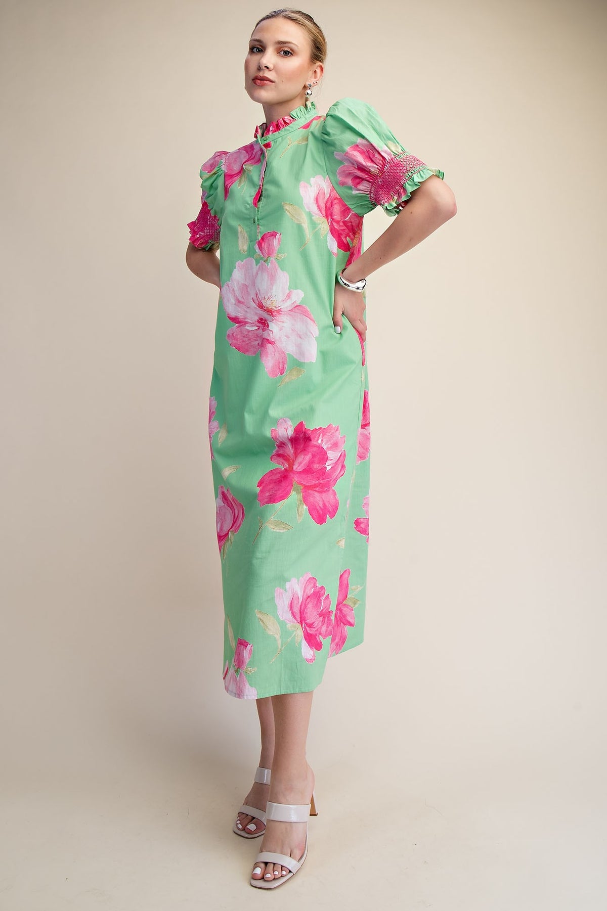Woman in a green midi dress with pink floral print, ruffle neck, and puff sleeves.