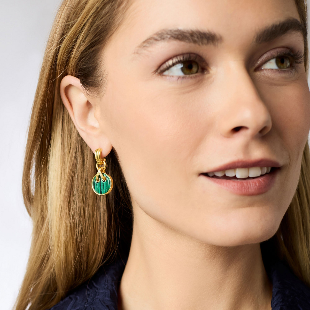 A woman wearing the Essex Hoop & Charm Earring in 24K gold plate with a green malachite charm.
