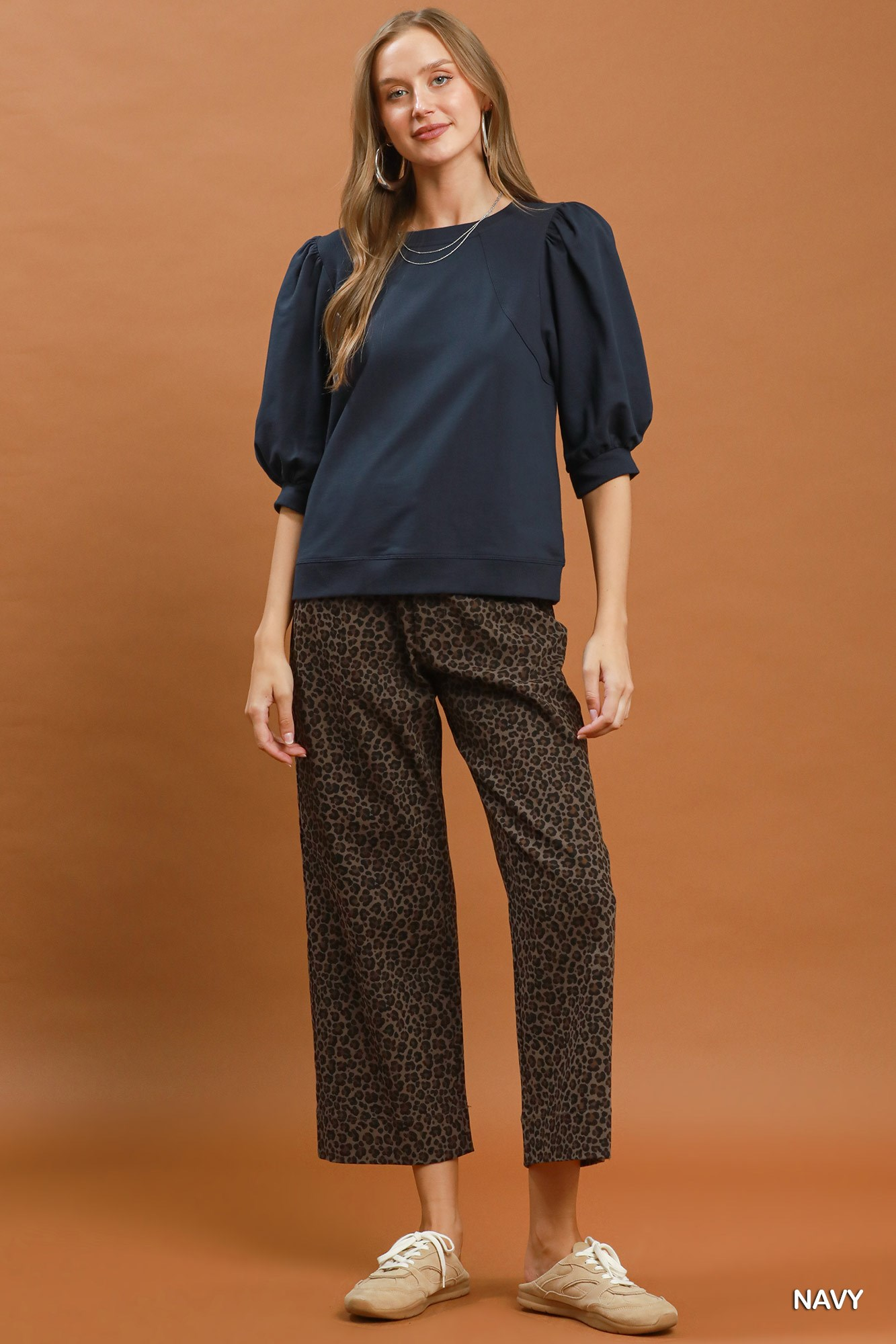 Woman wearing the Joyce navy blue puff sleeve pullover sweatshirt with leopard print pants.
