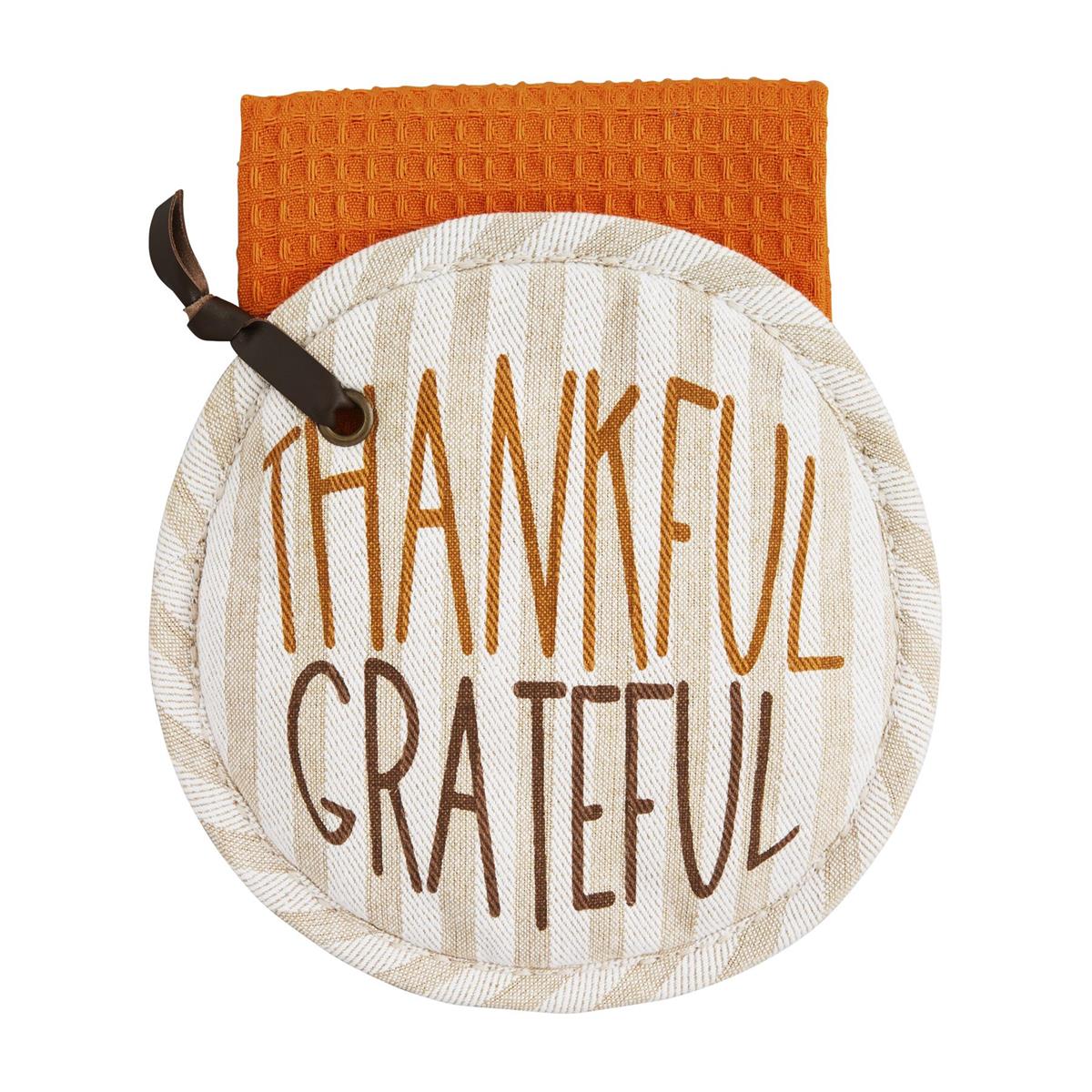 Round striped pot holder with 'THANKFUL GRATEFUL' embroidery and an orange waffle weave towel.