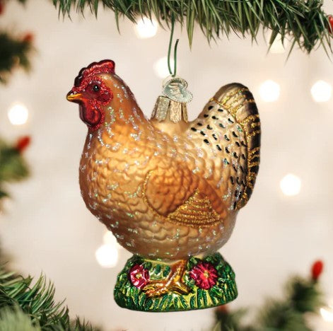 Glass Spring Chicken Christmas ornament with glitter accents hanging on a tree branch.