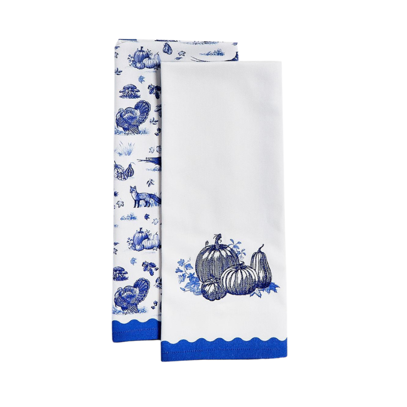 Two white cotton dish towels with blue toile patterns of pumpkins, turkeys, and foxes.