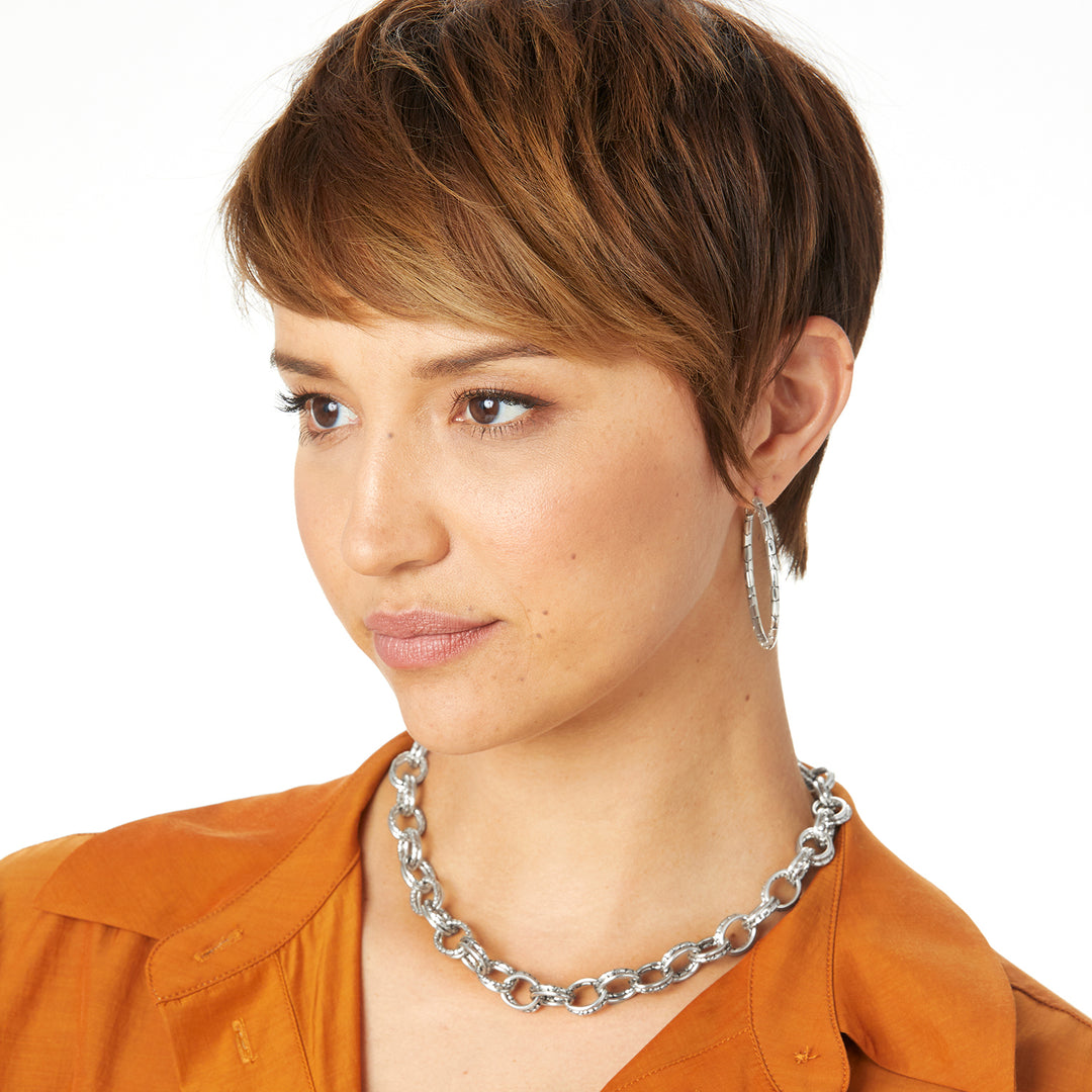 Woman wearing Pebble Large Hoop Earrings in silver with a textured pattern.