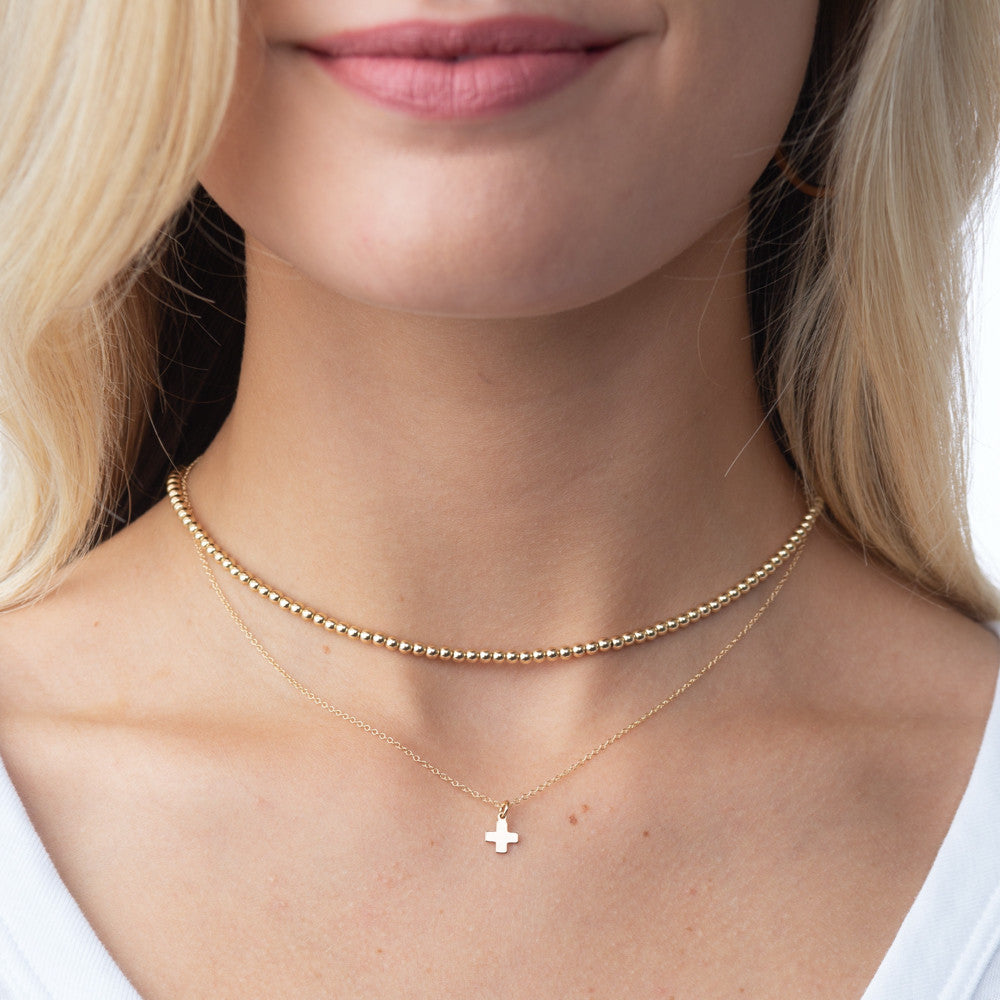 Classic gold choker necklace featuring a continuous strand of small round beads.