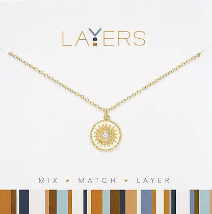 Gold White Starburst Coin Layers Necklace with a sun-shaped pendant and central crystal.