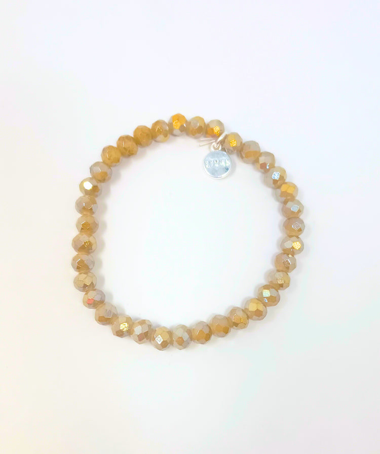Stretchy beaded bracelet with faceted gold glass beads and a small silver charm.