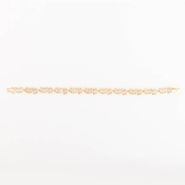 Gold-tone Remmy bracelet featuring a continuous row of angled baguette-cut clear crystals.