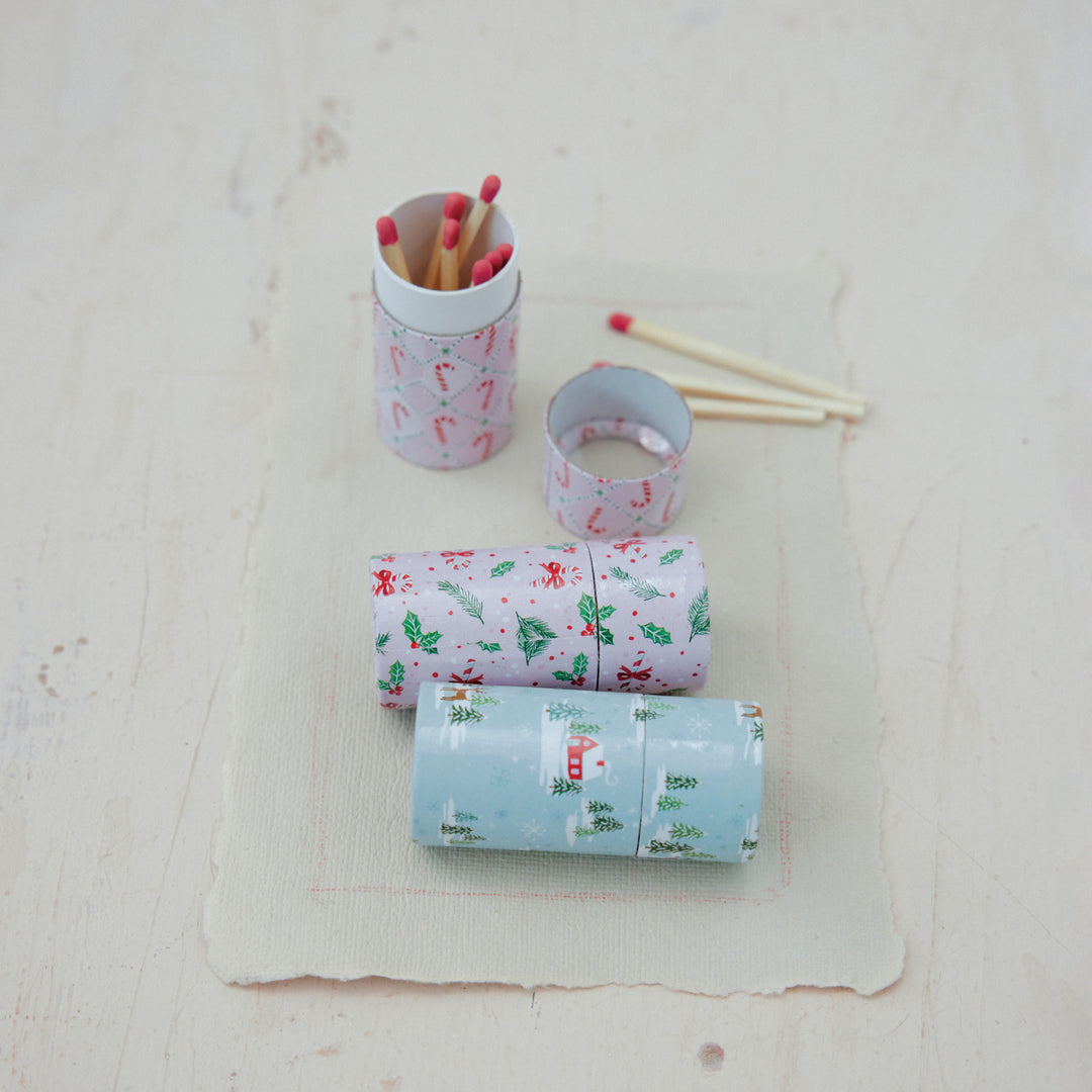 Safety matches in small tubes with holiday patterns including candy canes, holly, and winter scenes.
