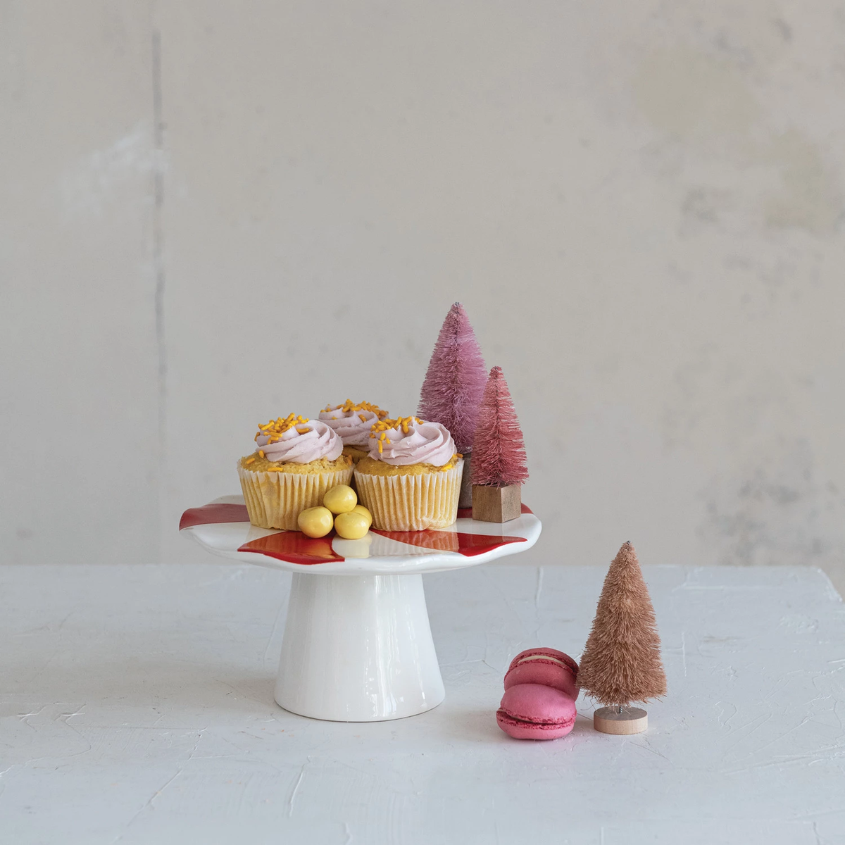 Ceramic peppermint candy shaped pedestal with red and white stripes, holding cupcakes and treats.
