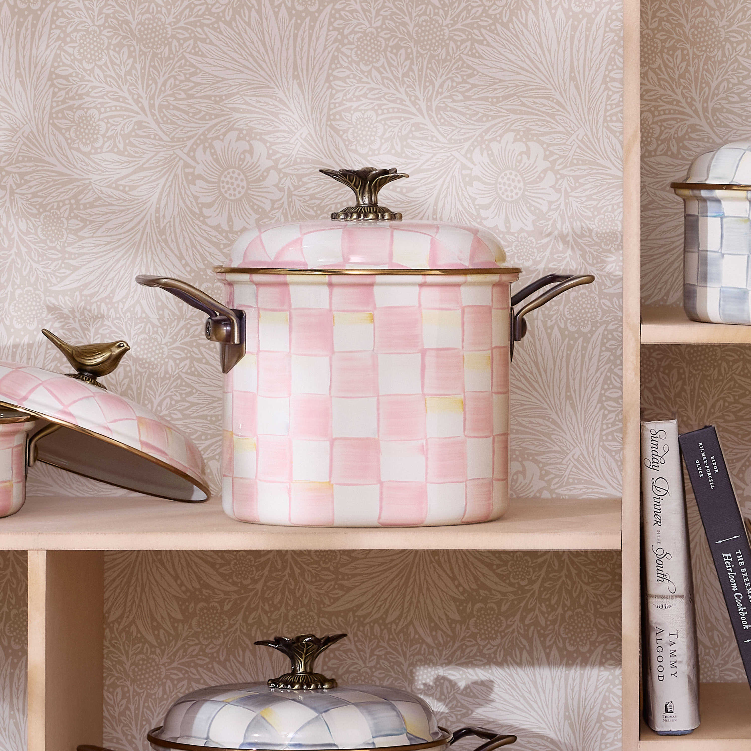Rosy Check 7 Qt. Stockpot with hand-painted pink and white checks on a shelf with cookbooks.