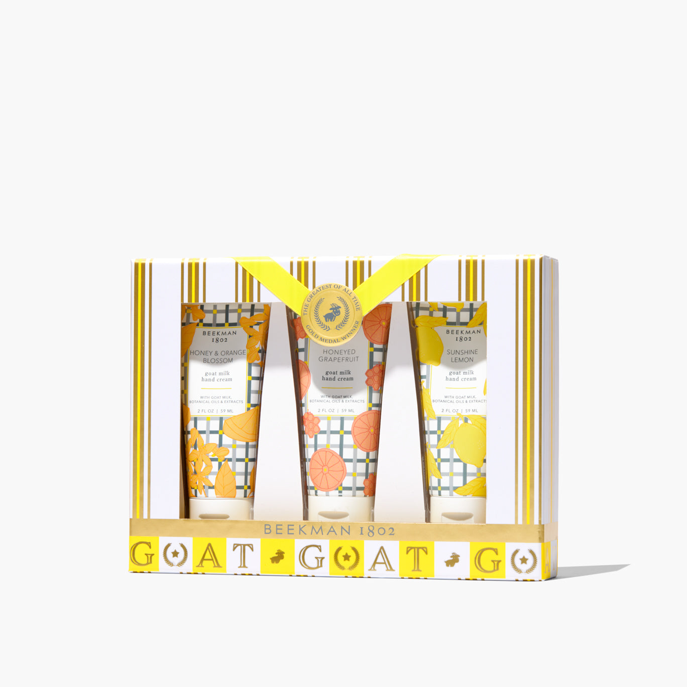 Three small hand cream tubes in honeyed grapefruit, sunshine lemon, and orange blossom scents arranged together.