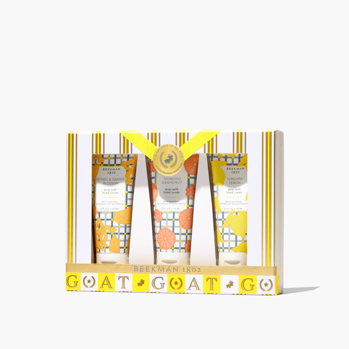 Three small hand cream tubes in honeyed grapefruit, sunshine lemon, and orange blossom scents arranged together.
